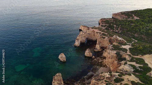 Sand beach among rocks on evening sunset. Ursa Beach near Arcos Naturais da Praia da Marinha at Atlantic Ocean coast in Portugal. Summer landscape. 