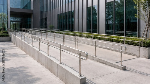Modern wheelchair accessibility ramp with stainless steel handrails outside a contemporary public building representing accessible architecture, universal design, mobility, safety.