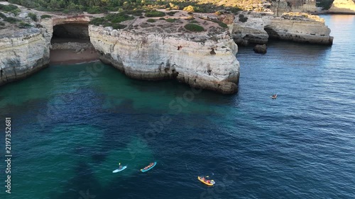 Sand beach among rocks on evening sunset. Ursa Beach near Arcos Naturais da Praia da Marinha at Atlantic Ocean coast in Portugal. Summer landscape. 