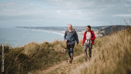 Two People Walking on a Hiking Trail Near the Ocean on a Cloudy Day