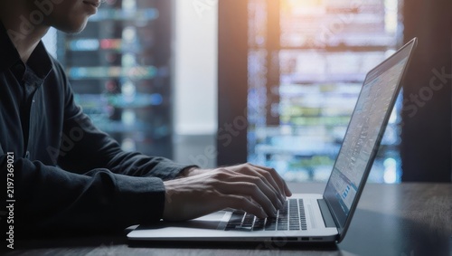Person working on laptop in modern office setting with bright window light.