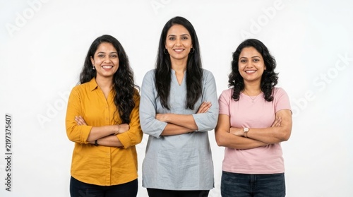 Three smiling confident indian women with arms crossed looking directly at the camera in a bright studio setting