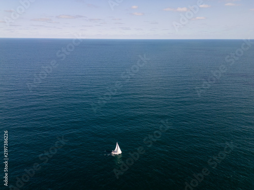 White Sailboat Sailing Alone on Open Blue Sea Ocean Horizon Aerial