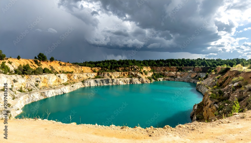 Obraz premium Scenic view of a turquoise crater lake with stormy clouds in the sky