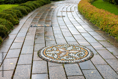 Wet stone path with a round pebble mosaic inlay in a park