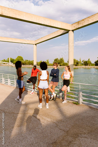 Fitness friends hanging out by a sunny park lake on a sports morning.
