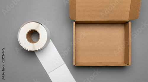 Blank thermal shipping label roll and open cardboard mailer box