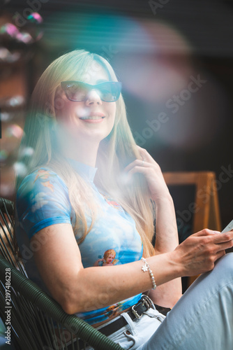 Happy Smiling Woman Relaxing at a Summer Cafe Terrace with Flying Soap Bubbles
