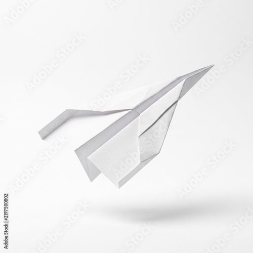 Minimalist white paper plane flying on white background, origami aircraft representing business startup and innovation, clean paper airplane concept