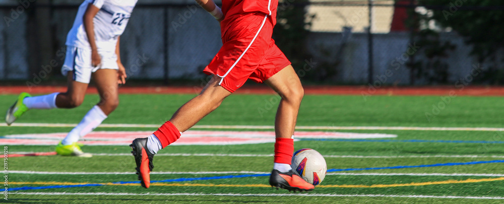 Obraz premium Soccer player dribbling the ball running down the field