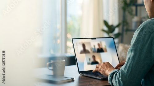 A person participating in a conference call on a laptop in a cozy home setting with video call laptop computer remote work online meeting home office working remotely digital conn