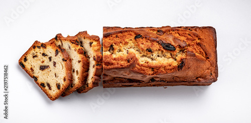 Baked loaf of bread with slices showing texture and ingredients on a white surface. Baked loaf of bread cut into slices shows a mix of ingredients inside the bread.
