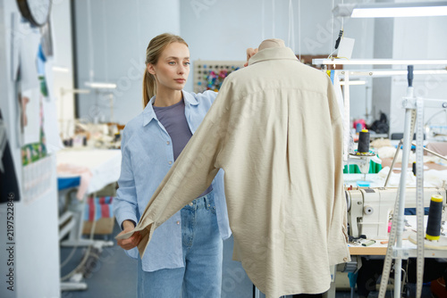 Fotografie Professional fashion artist precisely aligning and pinning shirt on mannequin in