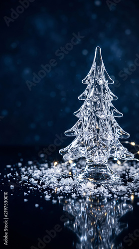transparent crystal Christmas tree sculpture on a reflective surface, surrounded by delicate ice crystals and tiny sparkling light 