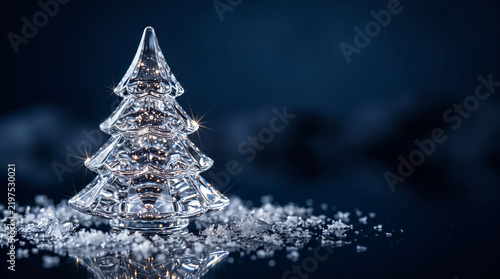 transparent crystal Christmas tree sculpture on a reflective surface, surrounded by delicate ice crystals and tiny sparkling light 