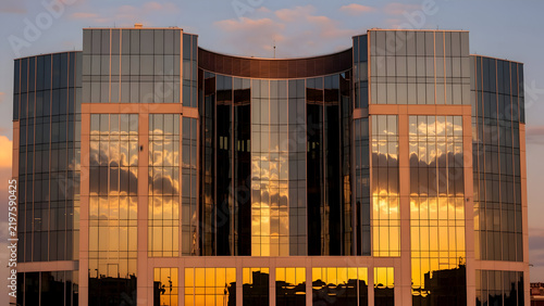 Modern glass office building reflecting vibrant sunset colors with sleek architecture and urban cityscape background