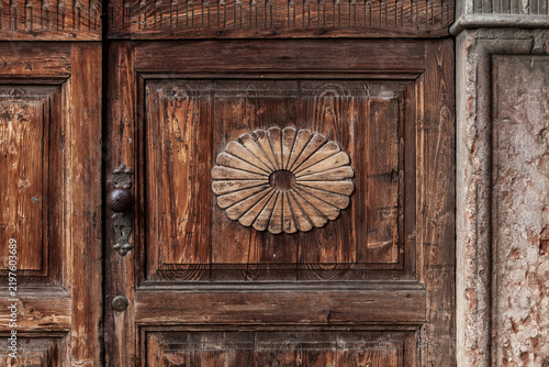 Heritage architecture and historical preservation antique wooden door with ornate carved floral medallion and weathered texture in traditional European building facade