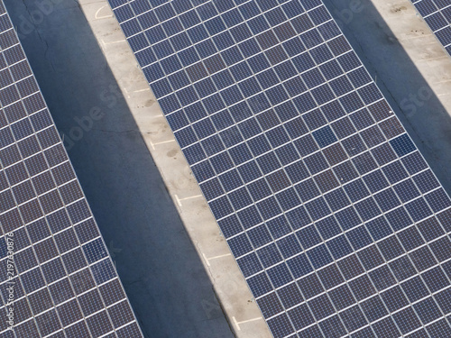 Drone view shows rows of solar panels set up in a parking area. The design supports electric mobility while promoting clean energy.