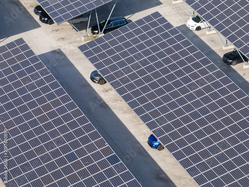 Aerial view of a solar parking area featuring solar panels and parked electric cars.