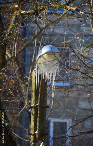 A street lamp covered in icicles in daylight. Winter natural beauty. Frozen precipitation on the lamp fixture.