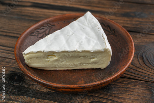 Delicious Brie Cheese Wedge on Rustic Wooden Plate Reflecting Gourmet Dairy Delicacies