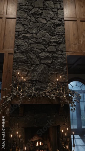 Stone fireplace with burning fire, candles, autumn garland, and pumpkins shown in changing interior decor scenes Vertical video