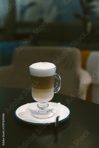 Bild auf Leinwand Layered latte macchiato with milk, coffee and thick foam served in a tall glass cup
