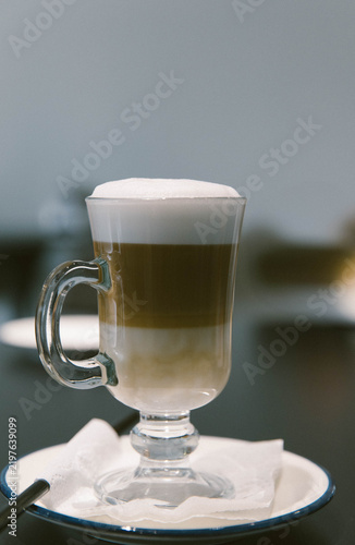 Bild auf Leinwand Layered latte macchiato with milk, coffee and thick foam served in a tall glass cup