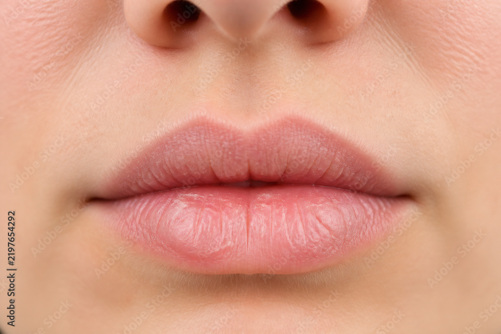 Obraz premium A close-up of a person's lips and nose is shown in a neutral setting.