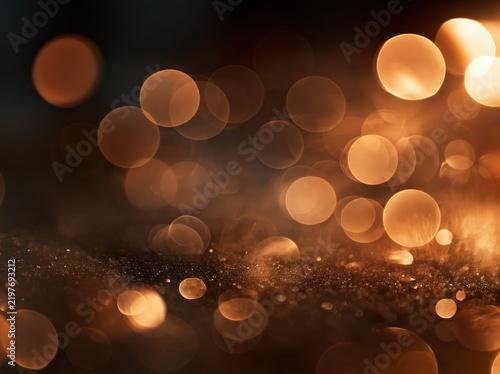 Golden bokeh light circles and glitter on dark background