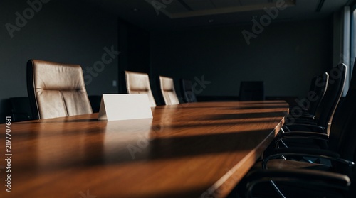 Quadro su tela Blank name card on dark boardroom table with leather chairs