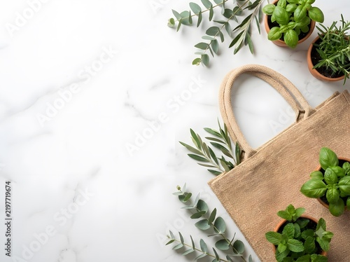 Natural jute tote bag with potted herbs and green leaves on marble background for minimalist lifestyle mockup