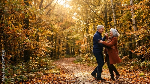 Happy senior couple dancing on a forest path during golden autumn day