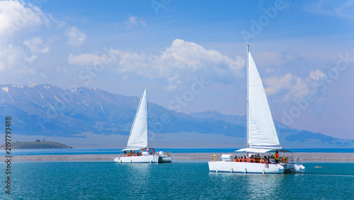 Картината върху платно Tourists Enjoying Catamaran Sailing on Sayram Lake, Xinjiang, China with Snow-ca