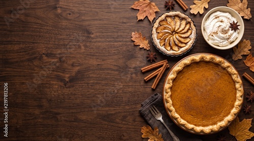 Autumn pumpkin pie and apple tart on dark wood background, rustic thanksgiving dessert table with fall leaves, seasonal holiday food flat lay