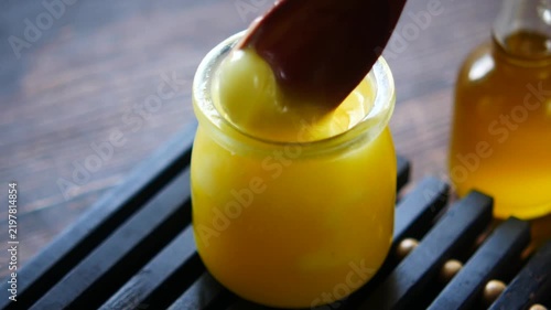 Close up of wooden spoon scooping homemade clarified butter from glass jar