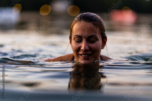 Фотография Woman enjoying a serene swim in a calm lake at sunset