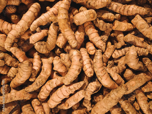 Fresh raw turmeric roots stacked together in a market background