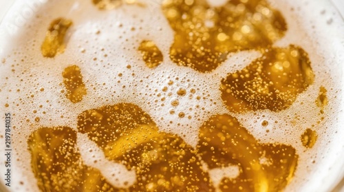 Close up of golden beer with frothy head and bubbles.