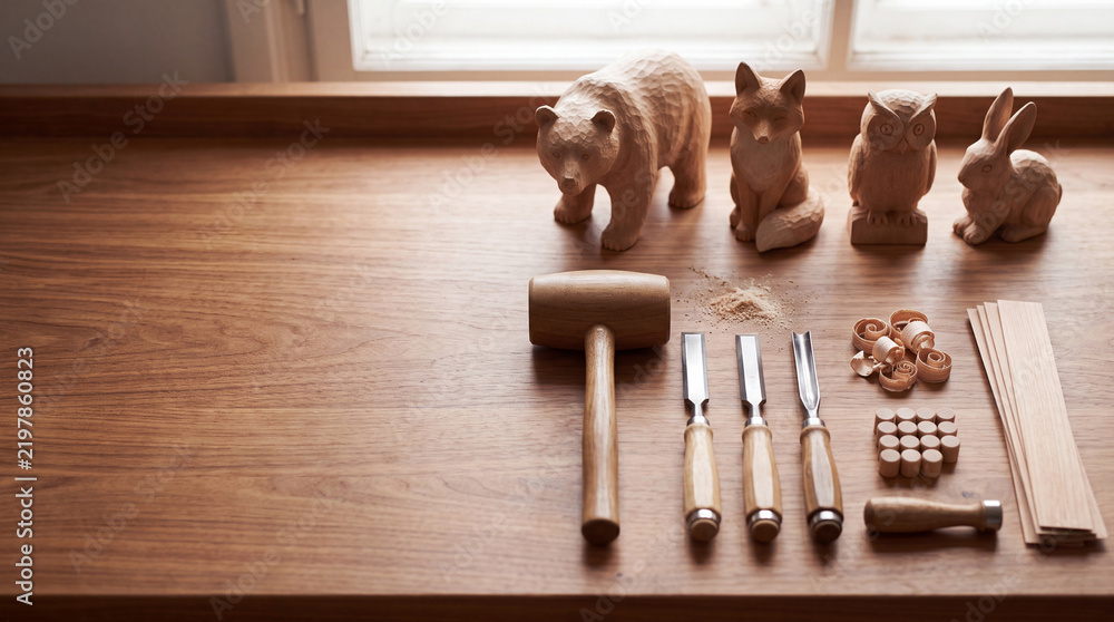Fototapeta premium Traditional Wood Carving Craft Workspace Featuring Handmade Wooden Animal Figurines, Professional Chisels, Mallet, and Wood Shavings on a Polished Timber Workbench in a Bright Creative Studio