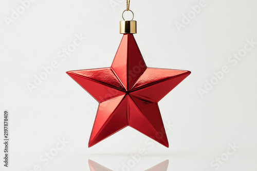 A striking red metallic star ornament, a classic symbol of festivity and aspiration, hangs suspended, its facets reflecting light, evoking a sense of holiday cheer and wonder.