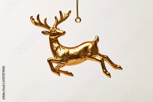 A gleaming golden reindeer ornament, captured in mid-leap, hangs suspended, its majestic antlers and dynamic pose exuding a festive and elegant charm.