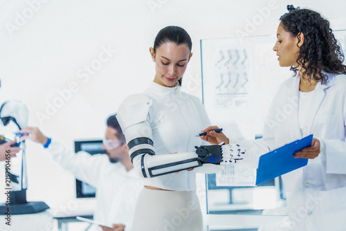 Foto Robotics R&D teamwork: a wearer flexes the black mechanical fingers of a body wo