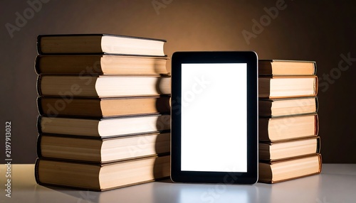 A black tablet next to stacks of old books
