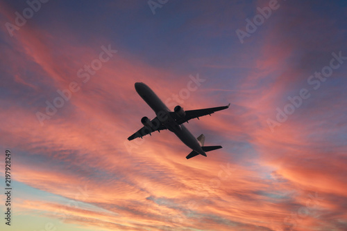 A passenger plane flying in the sky amidst sunset colors. Air transport. Aviation. Reasons for flight cancellations: Rain, storms, volcanic eruptions, war. Copy space, blank, empty. No people, nobody.