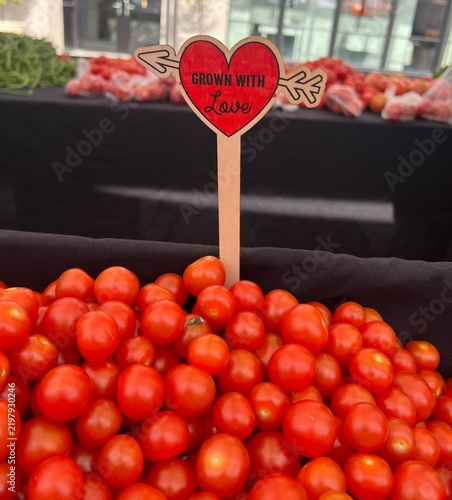 Fresh Cherry Tomatoes Pile At Farmers Market With Heart 'Grown With Love' Sign