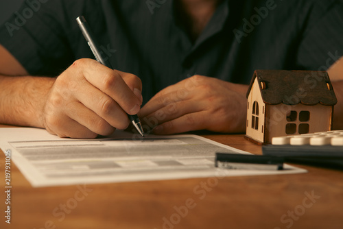 Fotografie Close up of house model, calculator and pen on wooden table.