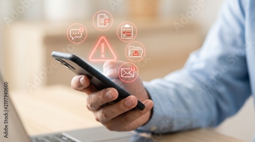Close up of hand using smartphone with cyber security warning alert notifications hovering above screen alert notification warning sign mobile security data breach digital threat hacker attack