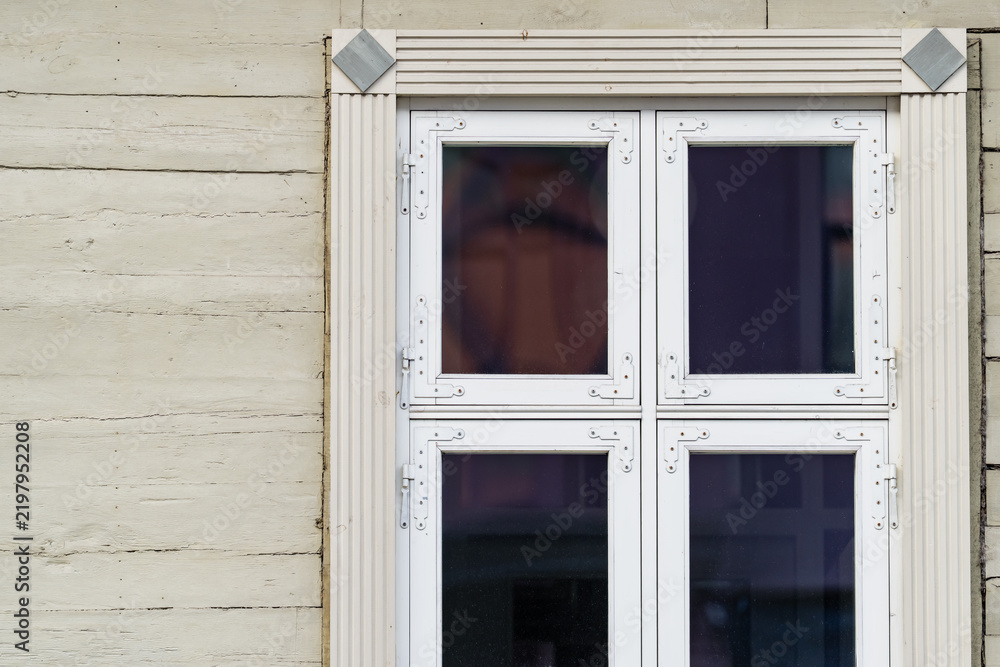 Fototapeta premium Multi pane timber window with decorative trim set into painted wooden cladding, illustrating traditional facade joinery and exterior building envelope components