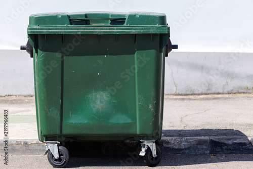 Фотография Green trash bin with wheels sits outdoors